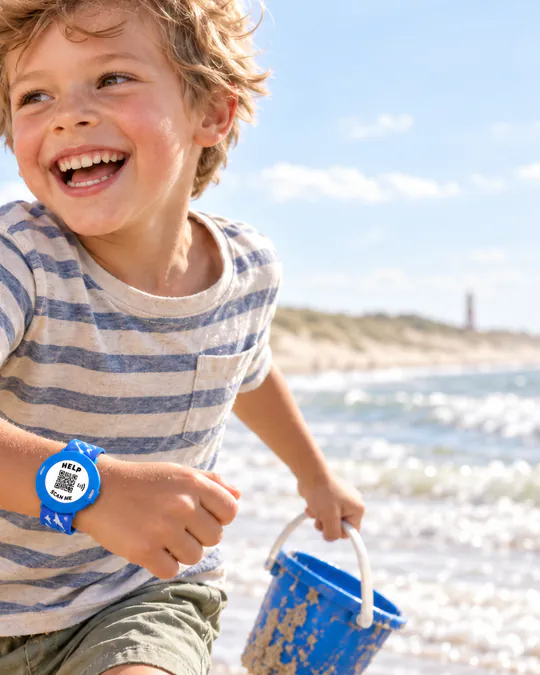 Een lachende jongen rent over het strand met een blauwe ICESCAN-armband om zijn pols.